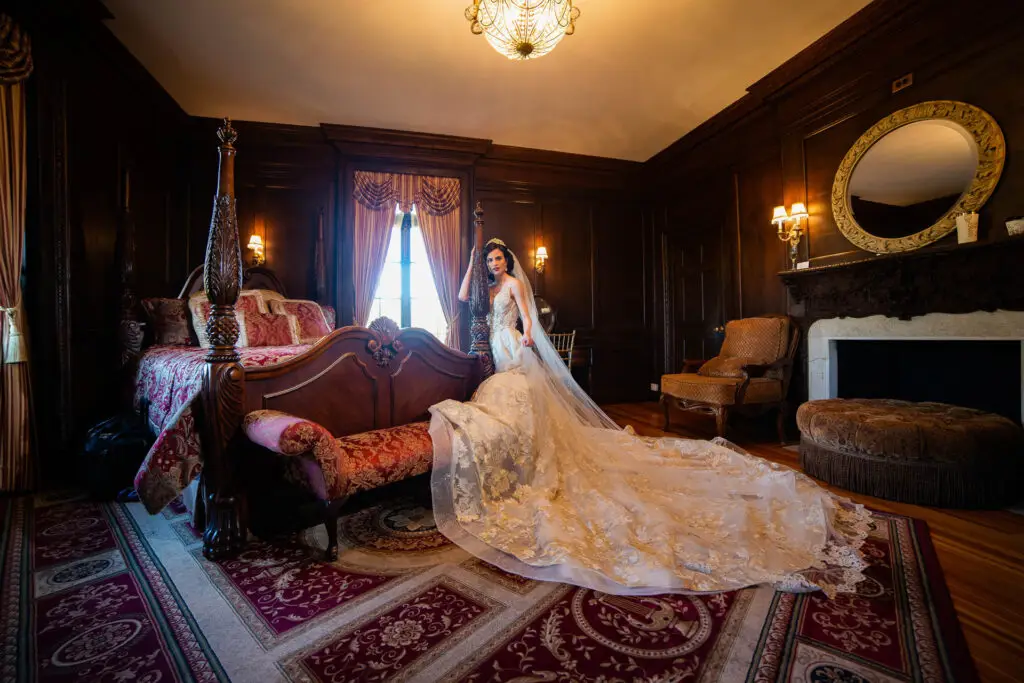 Elegant bride standing next to bed in de Seversky Mansion bridal suite
