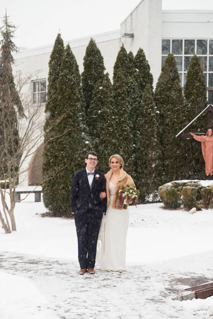 Snowy wedding portrait of bride and groom at church