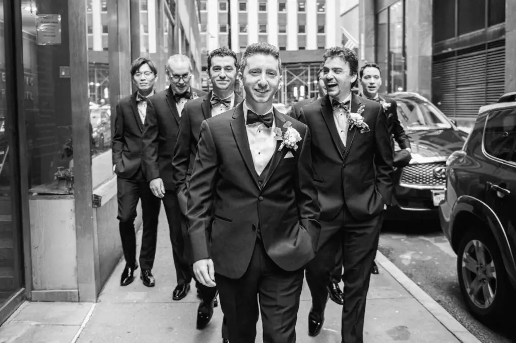 Stylish groom and groomsmen walking through the streets of NYC, captured in a candid wedding moment by JS Visions Photography