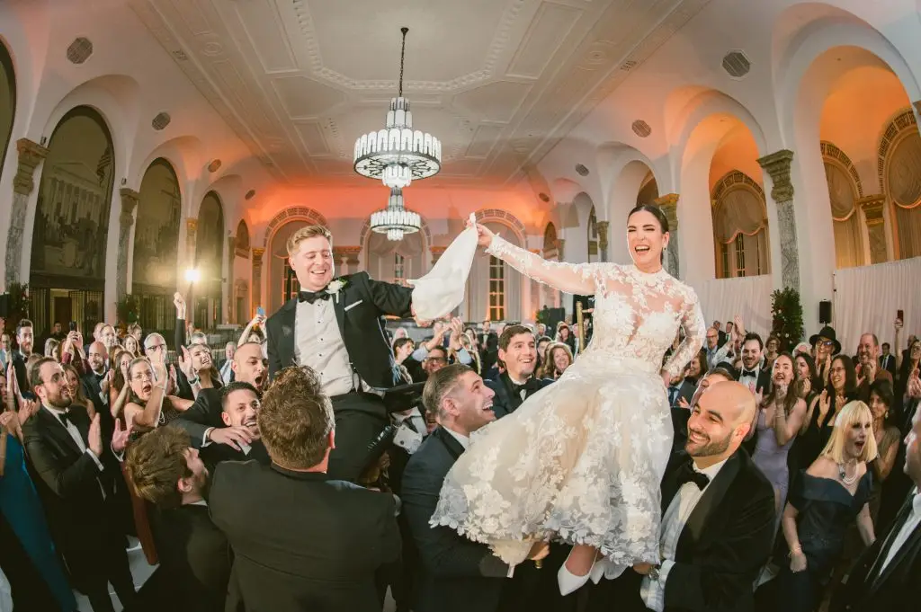 Traditional hora dance with couple hoisted on chairs at 48th Wall Street