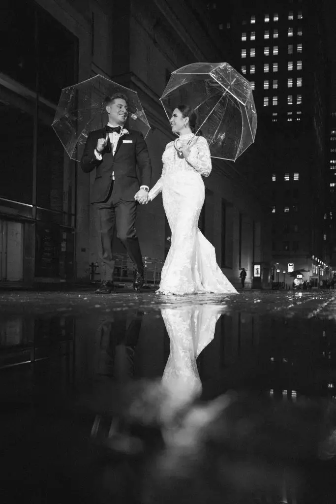 Romantic rainy night wedding photo of couple with umbrellas on Wall Street near 48th Wall St​