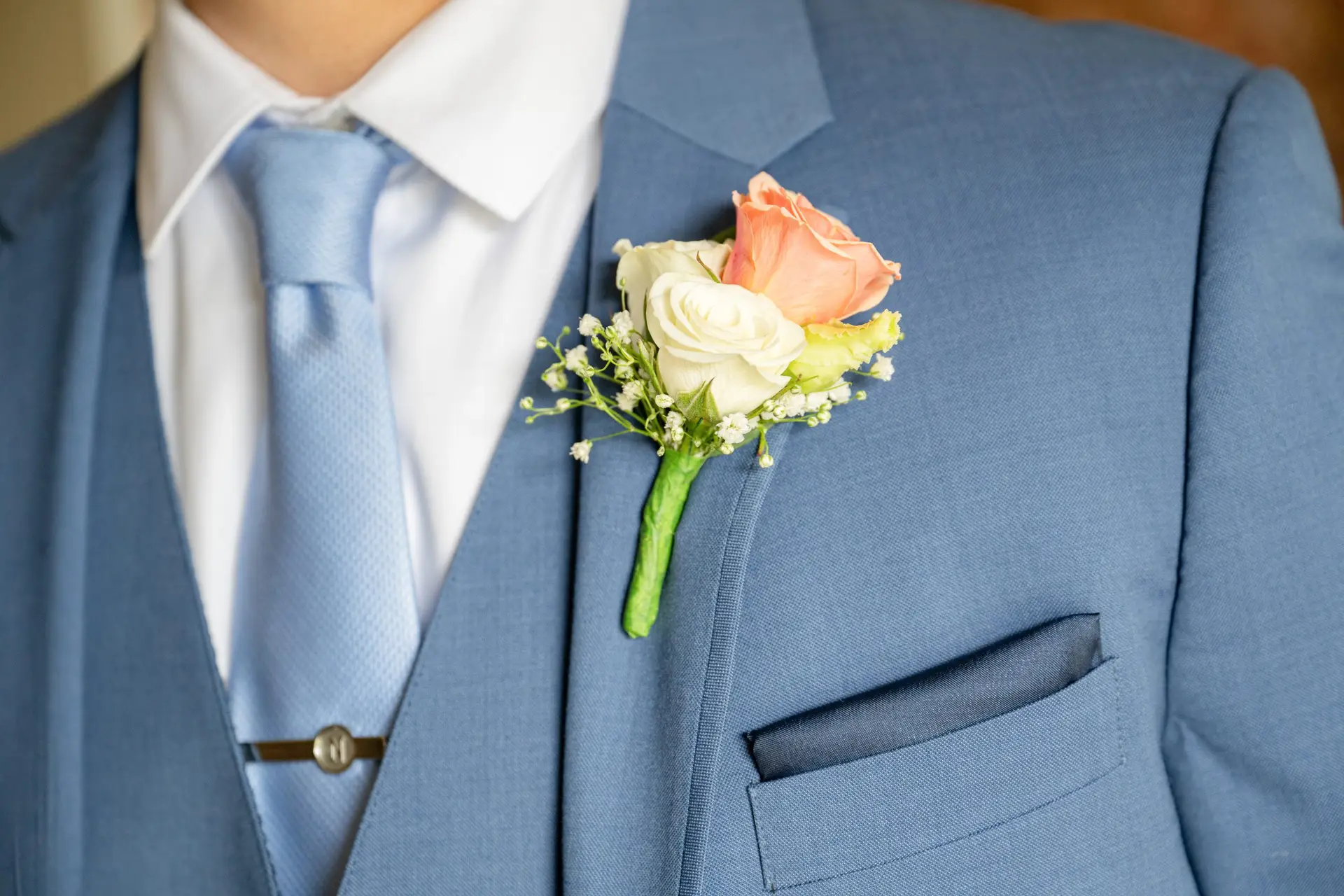 Groom's blue suit detail with light blue necktie, tie bar and rose boutonniere at a Long Island wedding