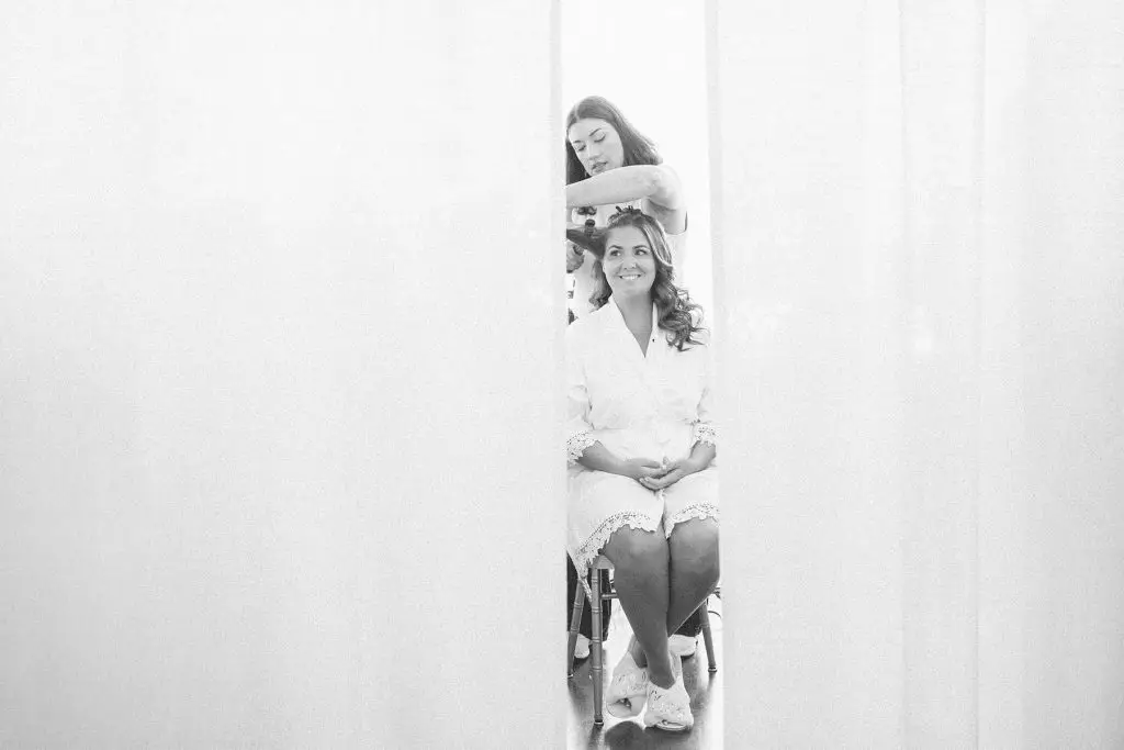 Black and white photo of bride getting hair done