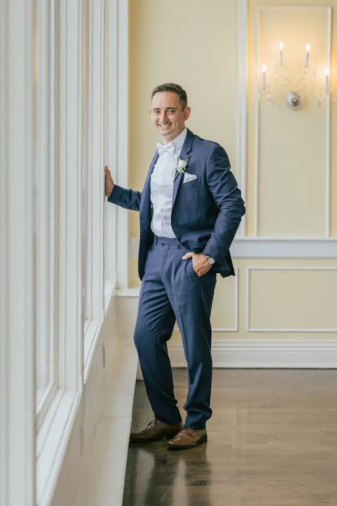Groom posing by window with soft natural light