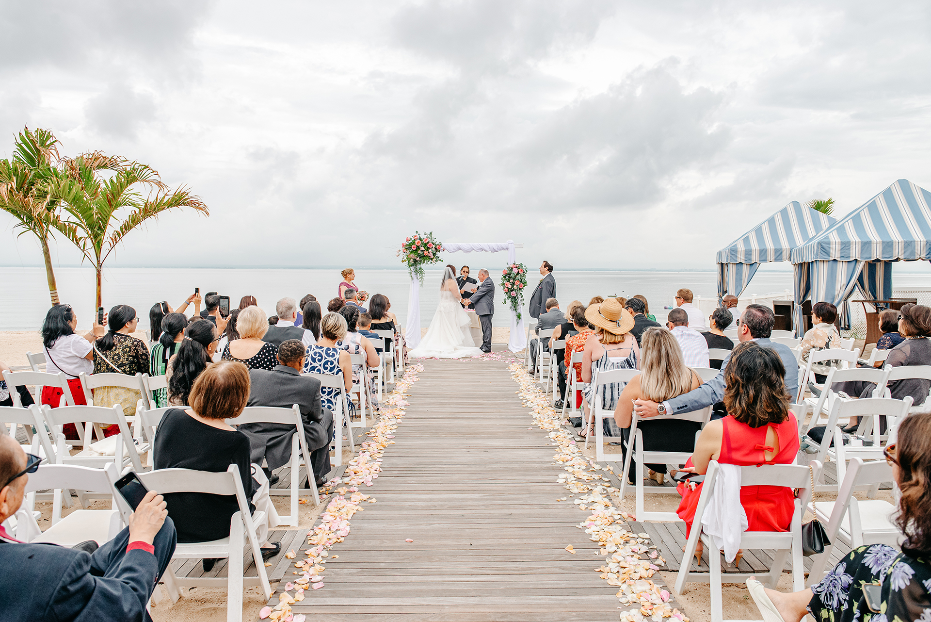 Outdoor waterfront wedding ceremony at Crescent Beach Club in Bayville, Long Island with bride and groom exchanging vows by the ocean