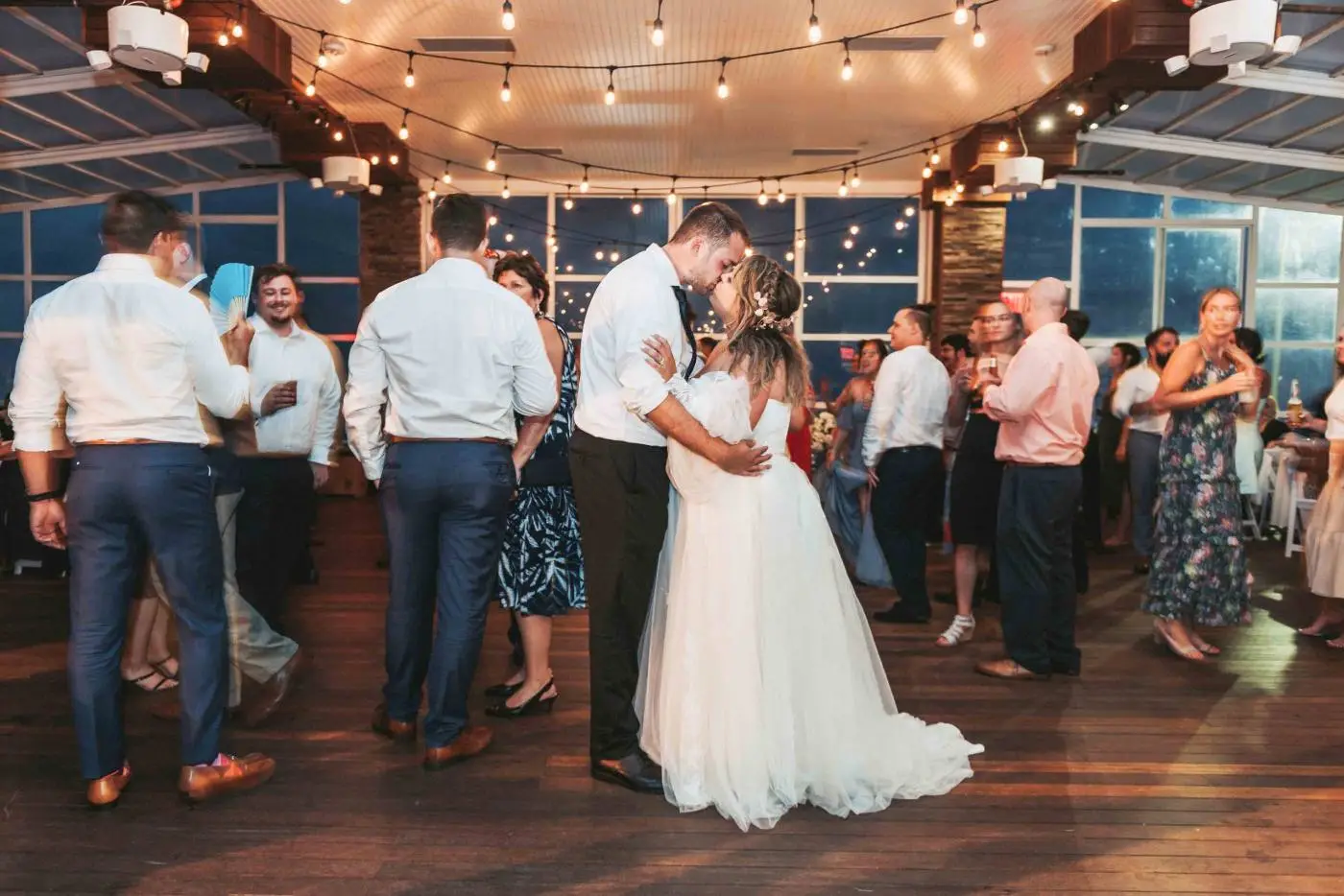 Bride and groom kissing on the dance floor under string lights at a Long Island wedding reception photographed by JS Visions