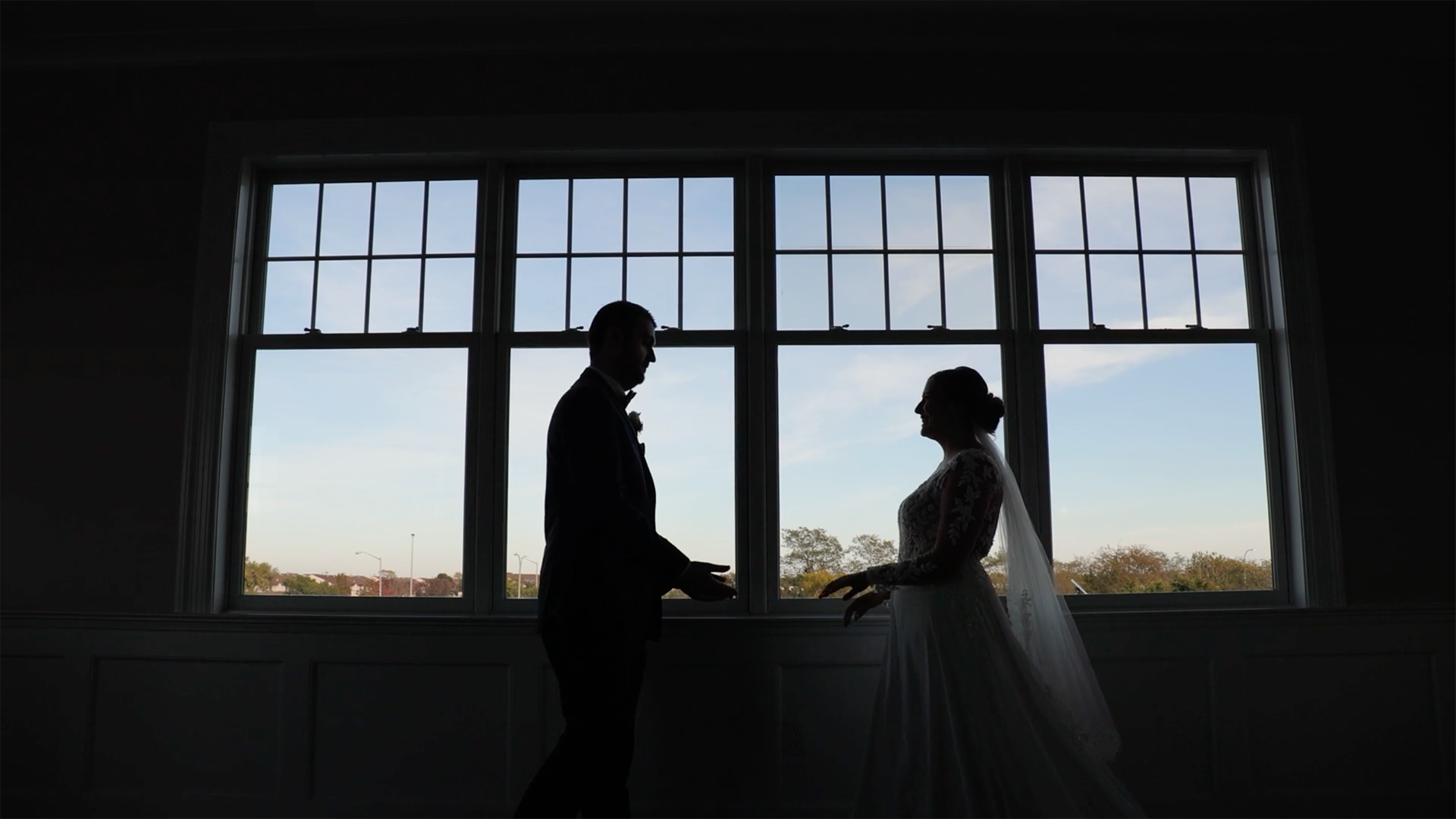 Bride and groom silhouette walking toward each other in front of large window during wedding day, elegant Long Island wedding photography moment