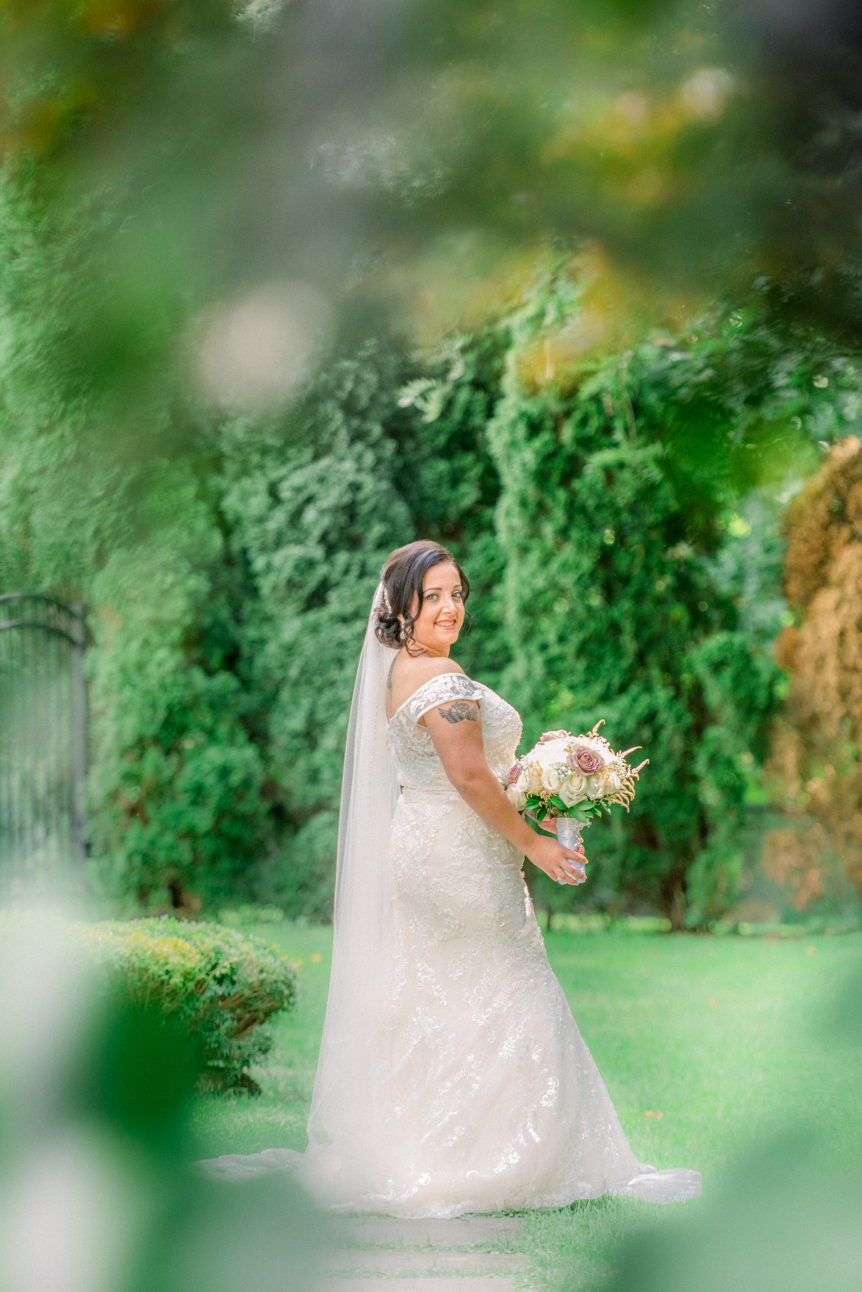 Bride holding her bouquet in the gardens of The Royalton Mansion, Roslyn Heights NY