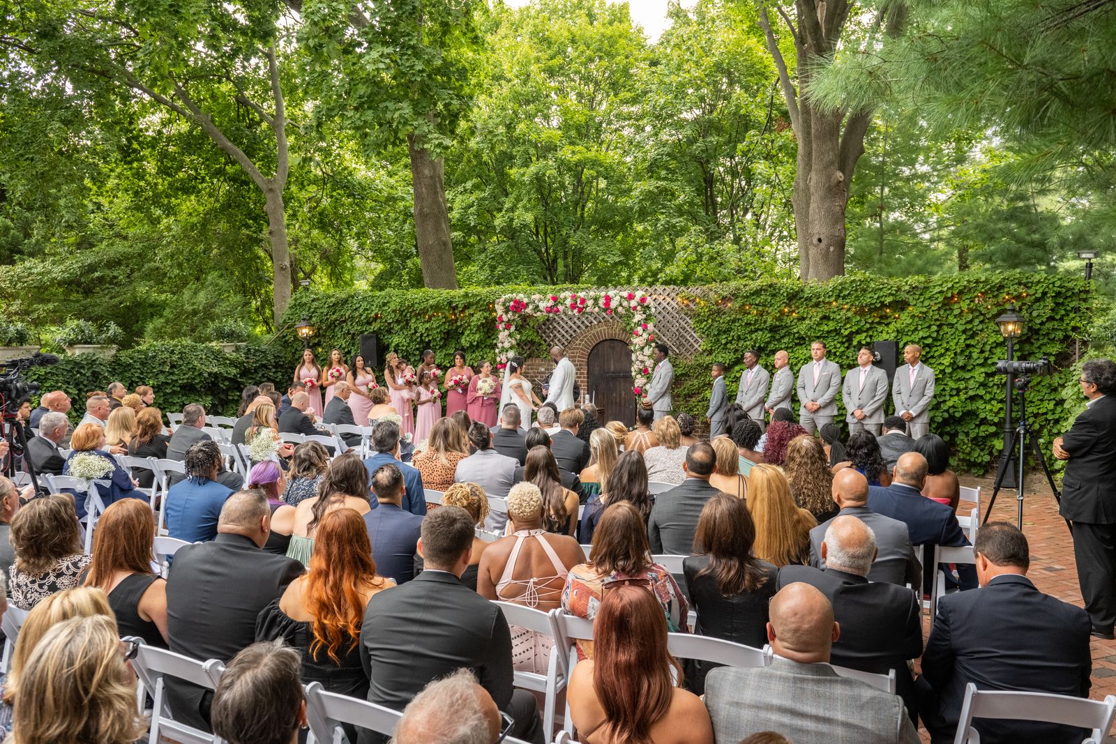 Guests watch an outdoor wedding ceremony in the gardens at The Royalton Mansion