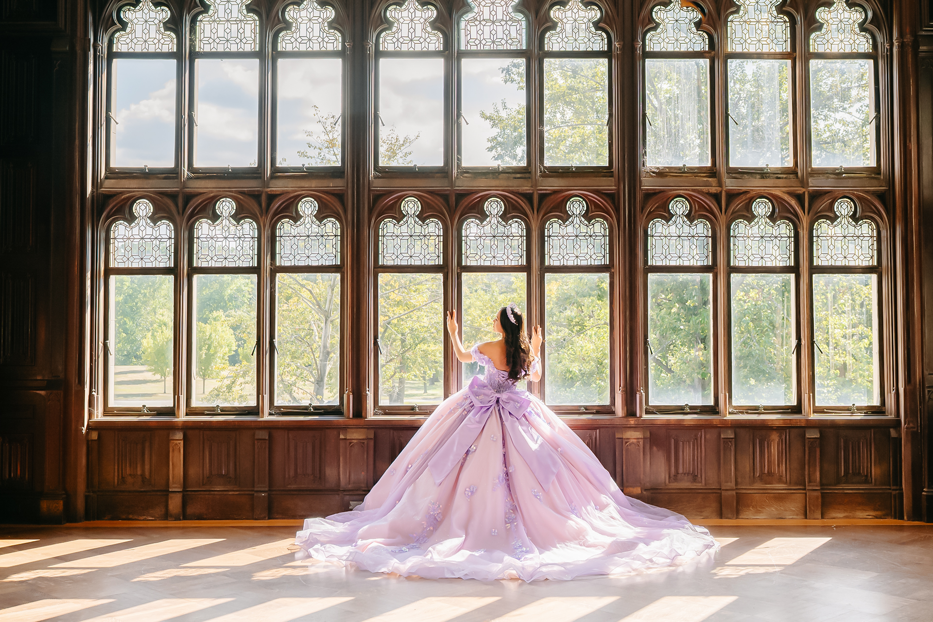Festejada de sweet 16 con un vestido lavanda de gala frente a los grandes ventanales históricos de Hempstead House en Sands Point Preserve.