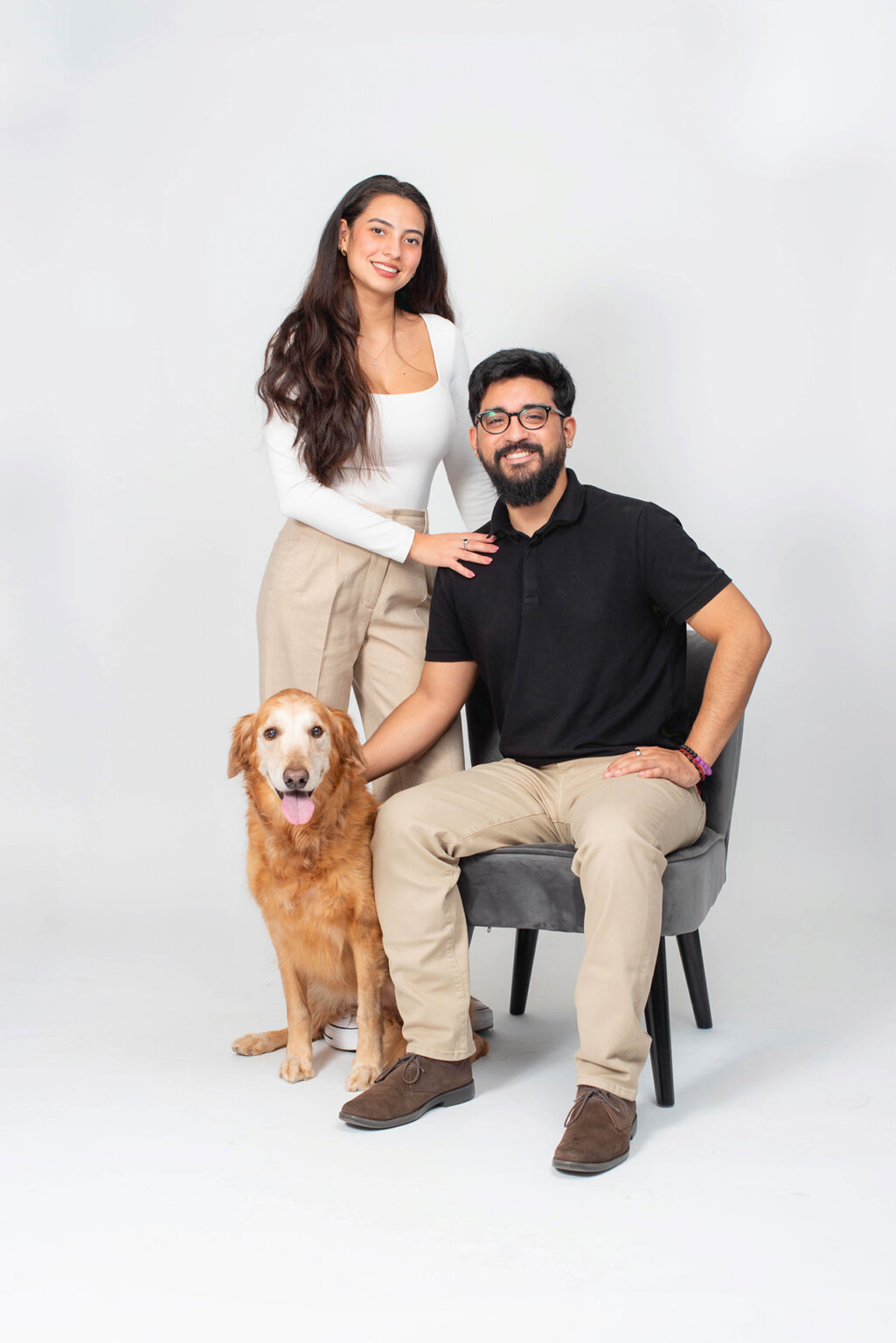 brother and sister posing with their golden retriever during a professional studio portrait session.