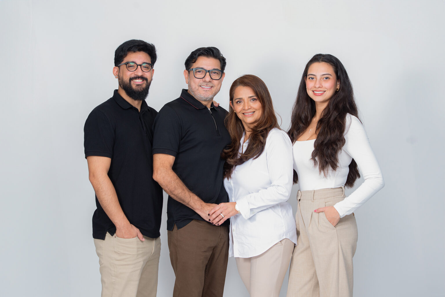 Family of four posing together in coordinated black, white, brown, and beige clothing during a Long Island studio session.